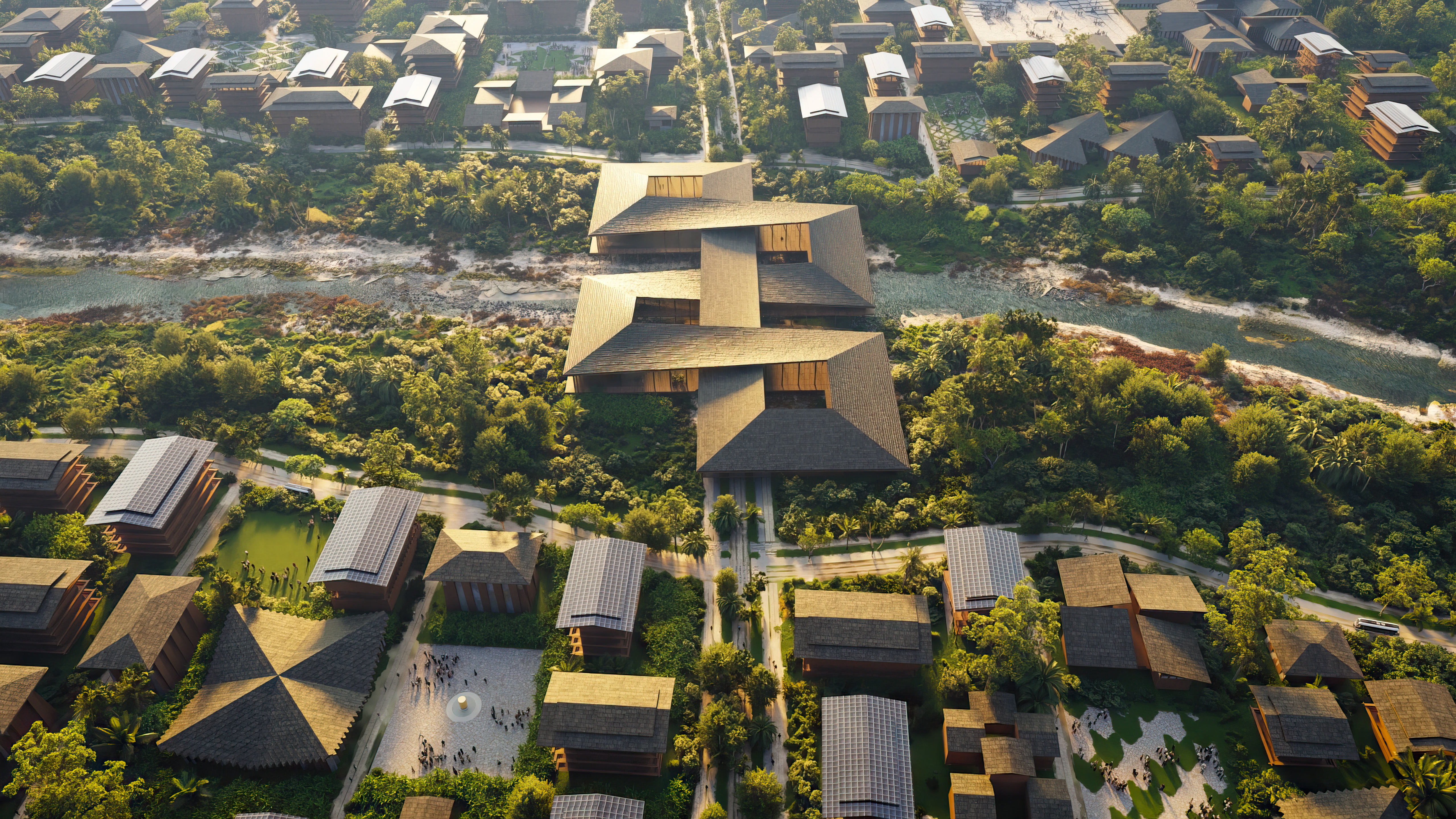 Aerial view of a sustainable community with various buildings, pathways, and greenery, centered around a large structure with dark-toned roofs, straddling a river.